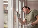 Man painting a window frame in white
