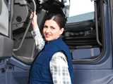 woman in blue sleeveless jacket about to climb up into a truck