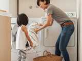 mother and child loading washing machine with laundry