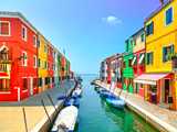 canal with moored boats in town with colorfull houses under a bright blue sky