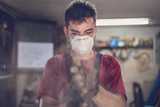 A young man wearing a mask to avoid dust while working in the garage