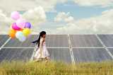 Girl running with colorful balloons with solar panels in the background