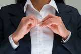 A woman fastening the last buttons on her blouse