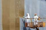 Men painting a large cargo ship