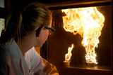Lab worker looking at burning test behind glas