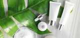 White cosmetic tubes, a dropper bottle, powder, and green leaves, representing biopolymer-based products.