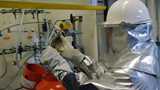 Man in protective clothing is filling a metal alkyl cylinder