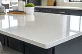 Sleek, modern kitchen countertop with a glossy, white/light grey quartz surface. 