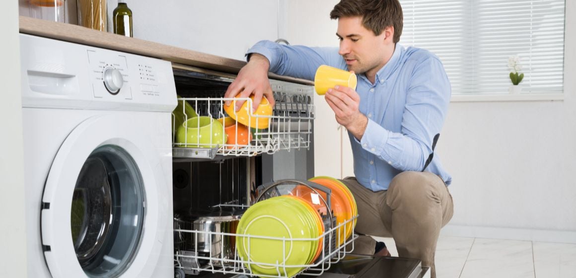 Young Happy Man Arranging Dishes In Dishwasher In Modern Kitchen. Nouryon’s technologies – surfactants, chelating agents, biopolymers, polymers – provides the functionalities to enhance detergents for automatic dishwashers. 