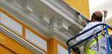 A man in a sky lift painting masonry on a building using silicate paint. Levasil colloidal silica and Bermocell CMC are added to silicate paint to improve paint stability, adhesion, durability and weather resistance. 