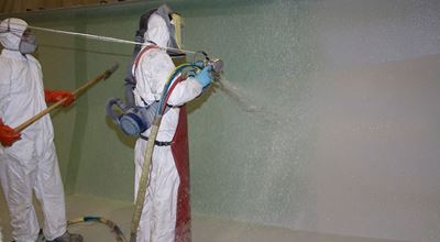 Workers with protective clothing are spraying-up wall