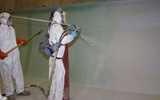 Workers with protective clothing are spraying-up wall