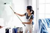 Girl painting wall with roller. 