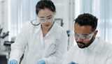Two people in lab coats with safety glasses