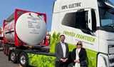 Two people standing in front of 100% electric truck